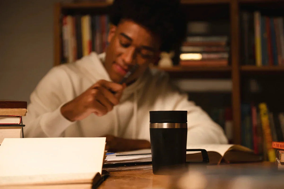 Uma pessoa sentada usando uma Mug Stanley para se aquecer com bebidas quentes durante o inverno.