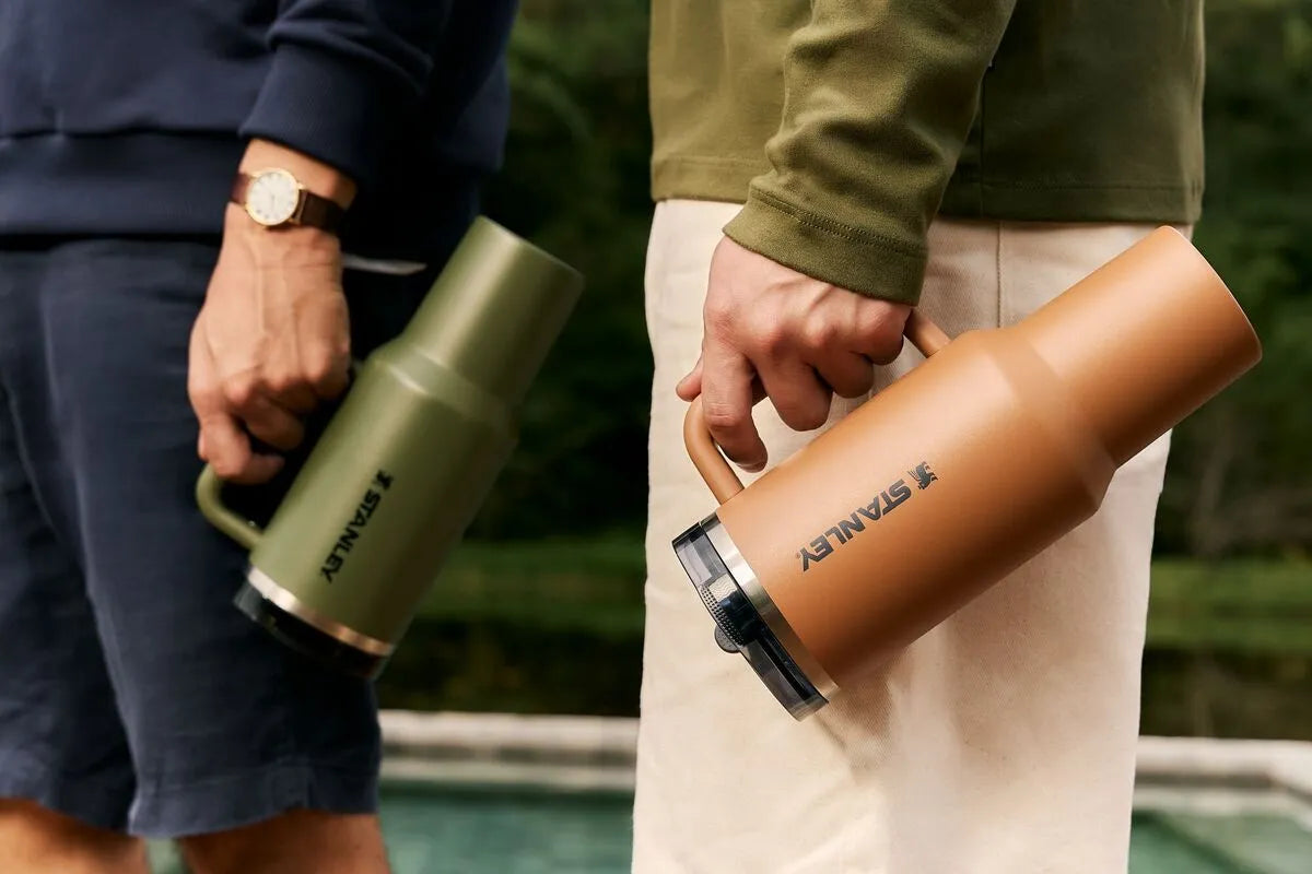 Duas pessoas segurando o Stanley Quencher e usando o copo para manter a hidratação em dia.