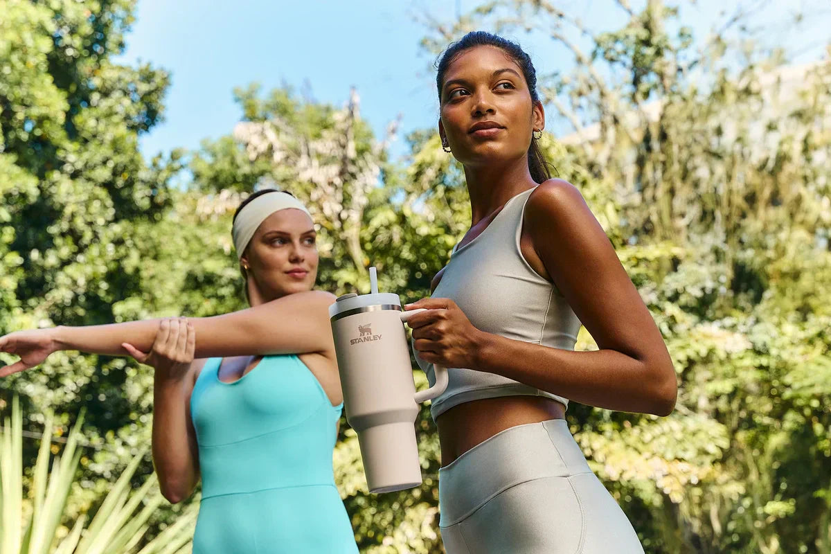 Duas mulheres fazendo esportes ao ar livre usando produtos Stanley.