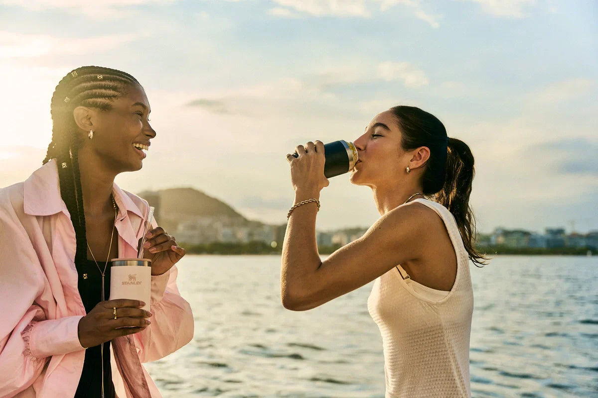 Duas amigas conversando enquanto usam o novo modelo do Can Cooler Stanley.
