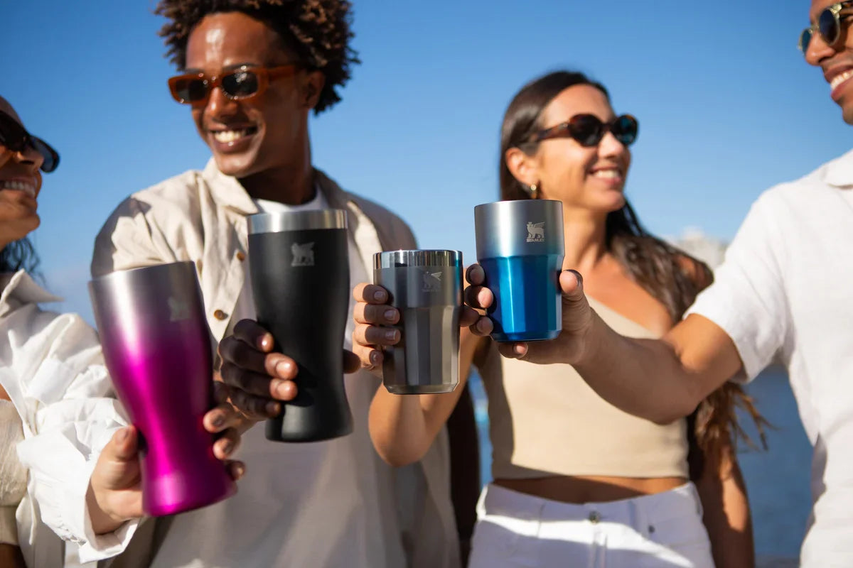 Quatro amigos brindando com seus copos Stanley sabendo como cuidar do item para durar por muito tempo.