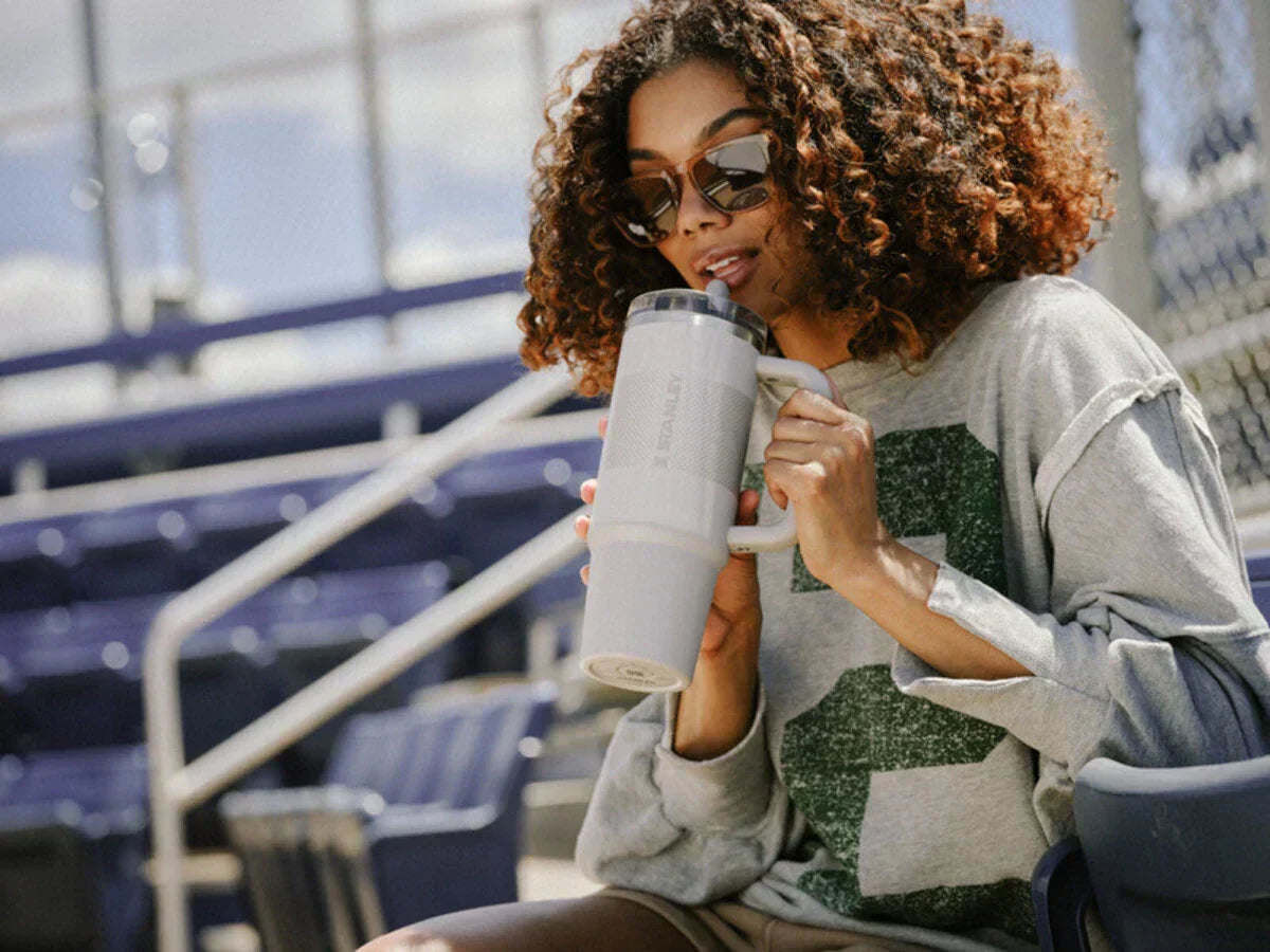 Uma mulher segurando o novo Quencher Pro Tour e se hidratando com ele.